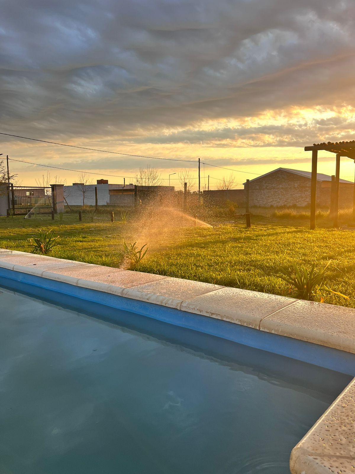 Vista de la pileta al atardecer con riego